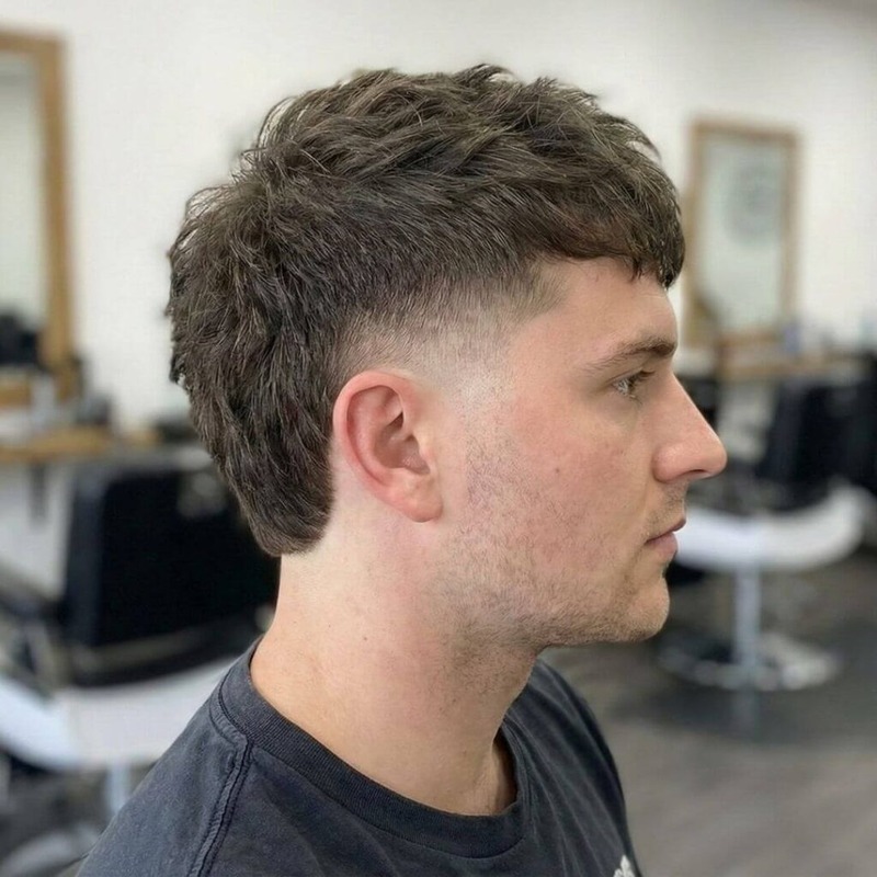 Young man with textured, choppy crop and low taper fade, hair styled forward