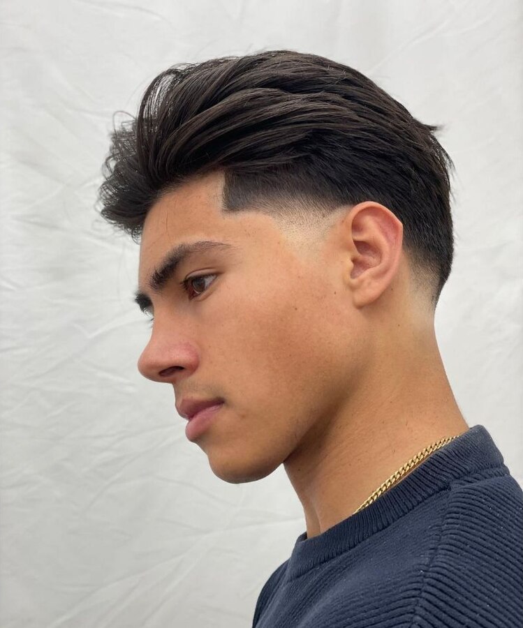 Medium slicked-back hairstyle with a clean burst fade rounding behind the ear