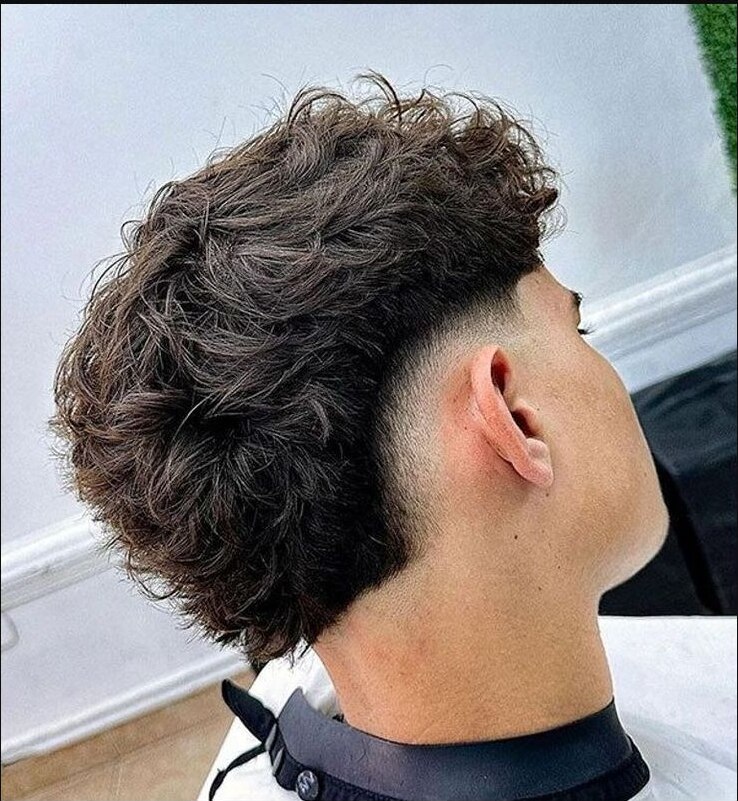Messy layered top with natural movement and a rounded burst fade behind the ear