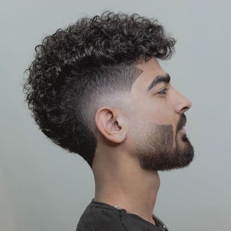 Natural curly hair with preserved top volume and a curved burst fade behind the ear