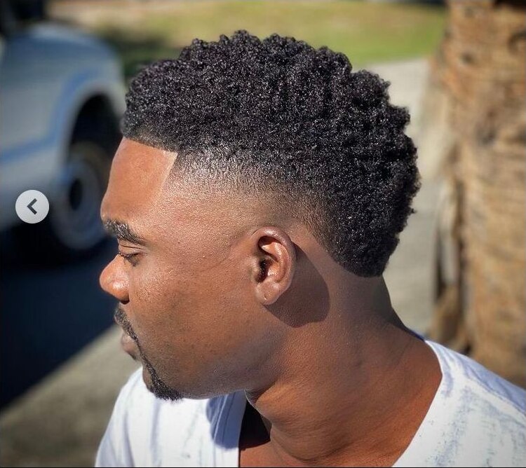 Short natural coils with a clean line-up and rounded burst fade behind the ear